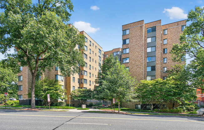 A street view of a residential area with apartment buildings and trees.