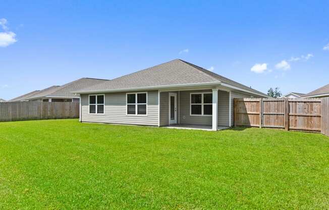 the backyard of a home with a large grassy yard and a wooden fence