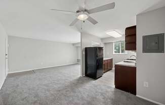 A spacious kitchen with a black refrigerator and a ceiling fan.