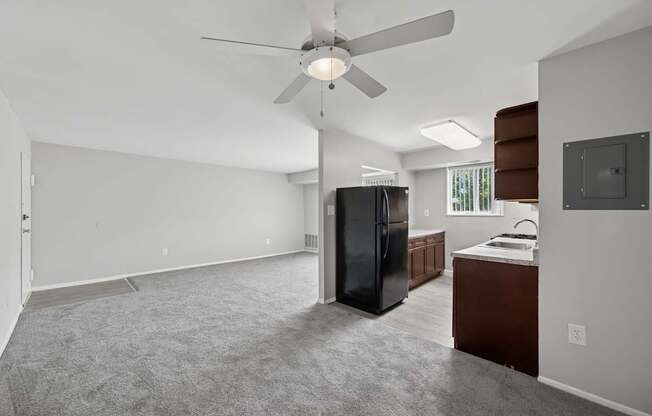 A spacious kitchen with a black refrigerator and a ceiling fan.
