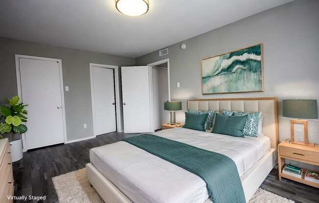 A bedroom with a large bed and a painting on the wall.