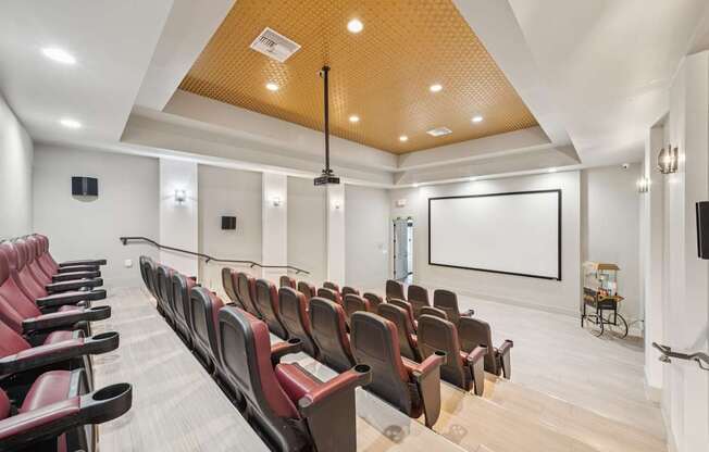 A large room with rows of red seats and a projector screen.