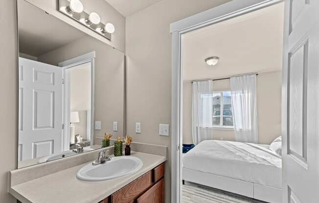 a bathroom with a mirror and a sink and a bedroom with a bed