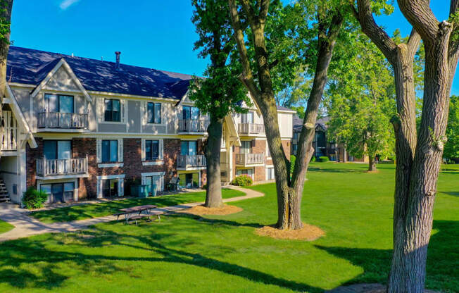 an exterior view of an apartment building with landscaped lawns and trees