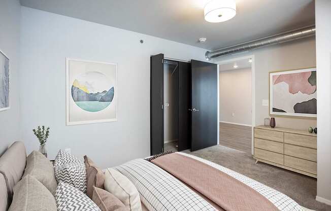 A bedroom with a bed, couch, and artwork on the walls.