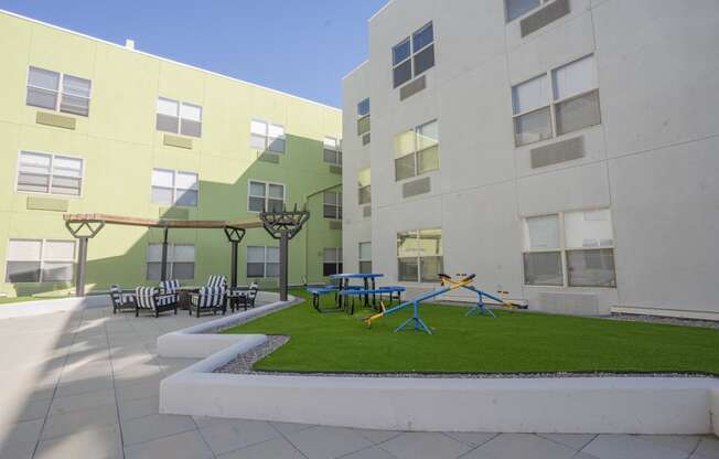 a courtyard with a playground and tables and chairs in an apartment building