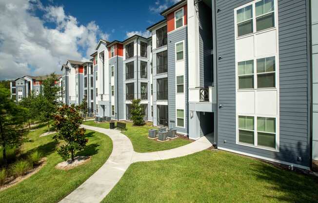 an exterior view of an apartment building with grass and trees
