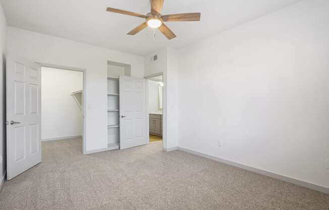 an empty bedroom with a ceiling fan and a closet