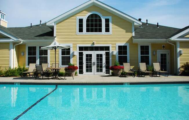 A yellow house with a pool in front.