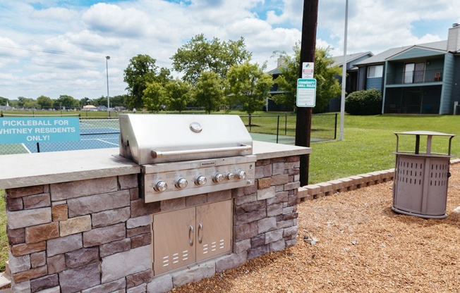 a barbecue grill in the backyard of a house with a tennis court