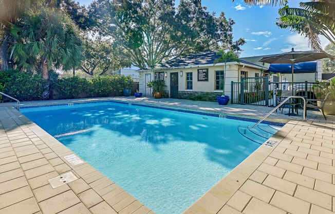 A swimming pool surrounded by a brick patio and trees.