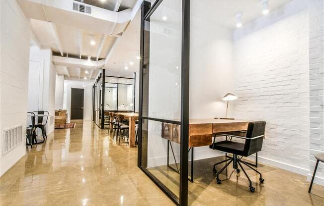 A modern office space with a glass partition and a long table with chairs.