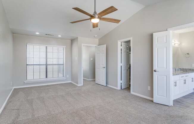 A spacious room with a ceiling fan and a carpeted floor.