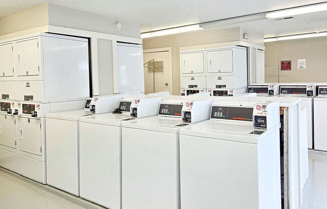 a row of white washing machines in a laundromat