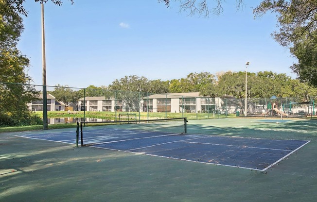 A tennis court surrounded by a fence and trees.