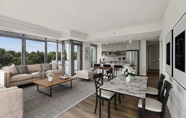 a living room with couches and a table and a kitchen with a large window