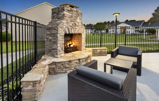 an outdoor patio with a stone fireplace and a table and chairs