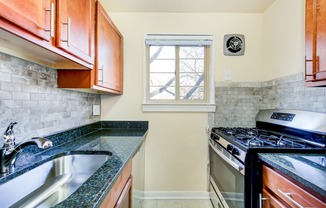 kitchen with wood cabinetry, gas range, tile backsplash, and window at cambridge square apartments in bethesda md