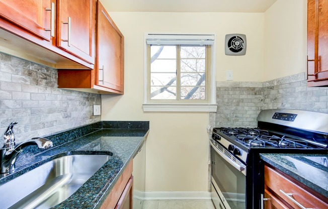 kitchen with wood cabinetry, gas range, tile backsplash, and window at cambridge square apartments in bethesda md