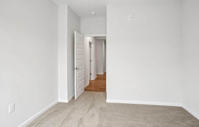 A hallway with a carpeted floor and white walls.