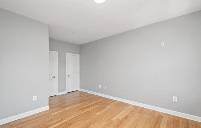 a bedroom with grey walls and a wooden floor