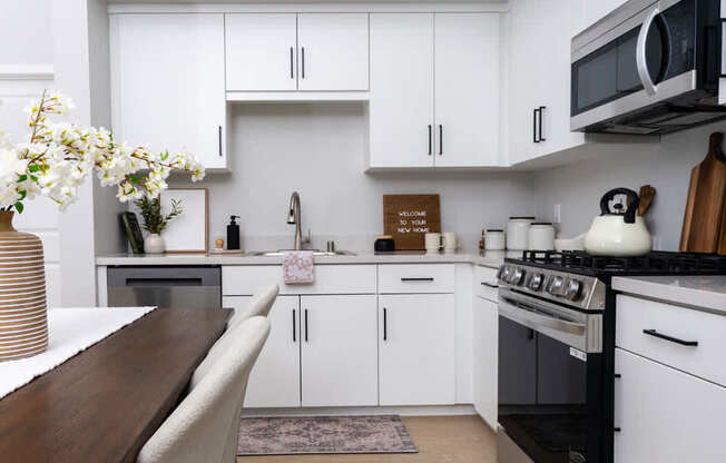 A kitchen with white cabinets and a wooden table.