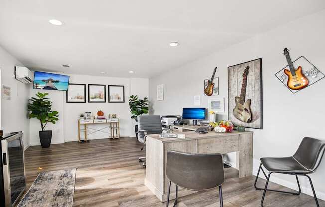 A room with a desk, chairs, and guitars on the wall.