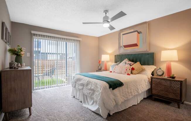 Large bedroom in Stadium 700 apartments in Arlington, TX with queen bed, ceiling fan, and large sliding glass door