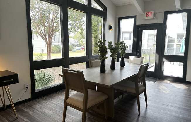 a dining room with a table and chairs and large windows