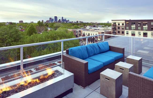 a rooftop patio with a blue couch and a fire pit