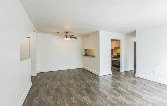 A room with a ceiling fan and wood flooring.