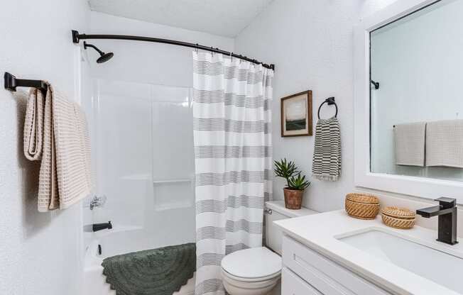 a white bathroom with a striped shower curtain and a white toilet