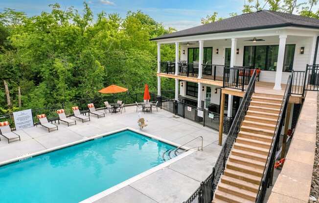a swimming pool in front of a house with a pool and a porch