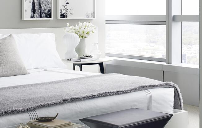 A modern bedroom with a large bed and a small table with a vase of flowers on it.