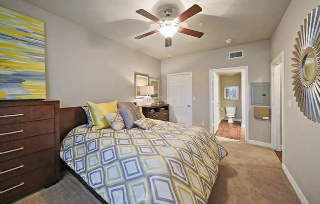 A bedroom with a bed, dresser, mirror, and a painting on the wall.