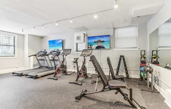 A spacious gym with treadmills, exercise bikes, and weight racks.