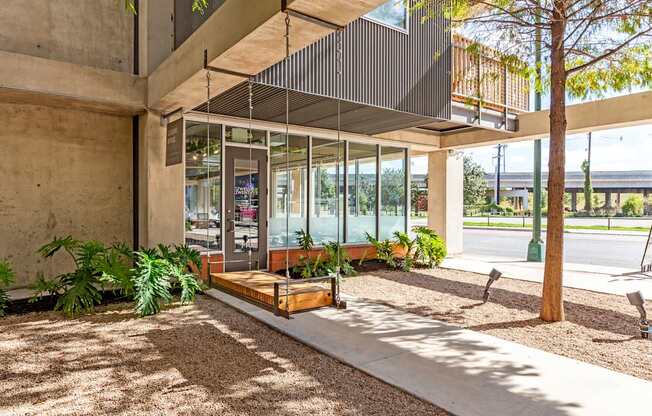 A modern building with a glass entrance and a tree in front.