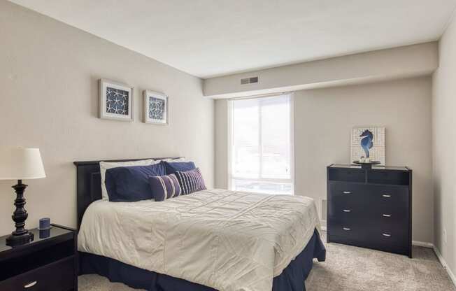 a bedroom with a bed and a dresser and a window at Bayville Apartments, Virginia