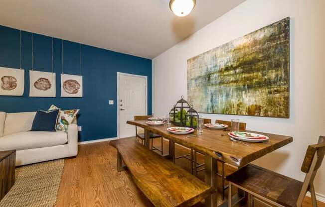 a dining room with a wooden table and bench and a couch in the background at Villa Espada Apartments, San Antonio, 78221