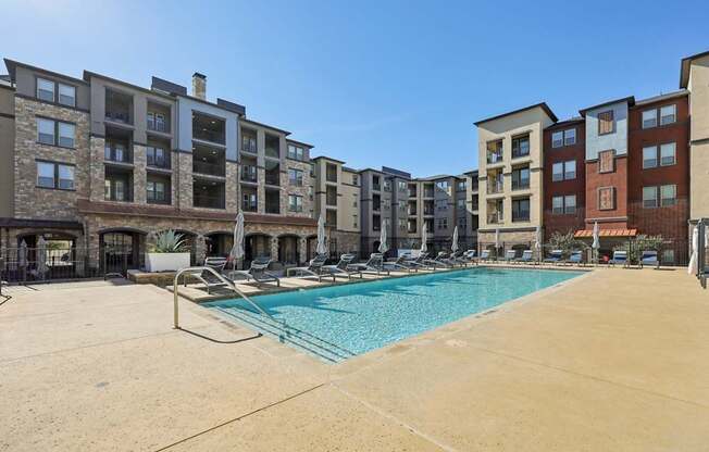 A large swimming pool is surrounded by apartment buildings.