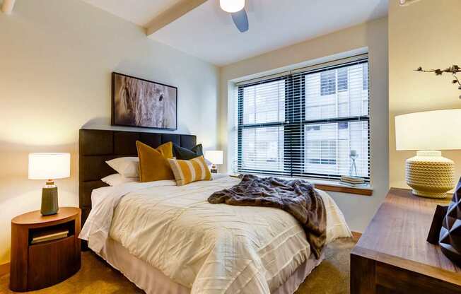 A bedroom with a bed, nightstand, and window.