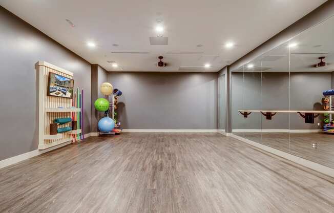 a workout room with a mirrored wall and wooden bookshelf