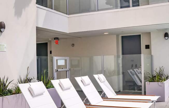a row of white chaise lounges in front of a white building