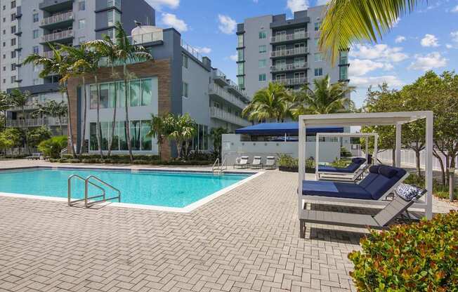 A pool area with a sun lounger and a building in the background.