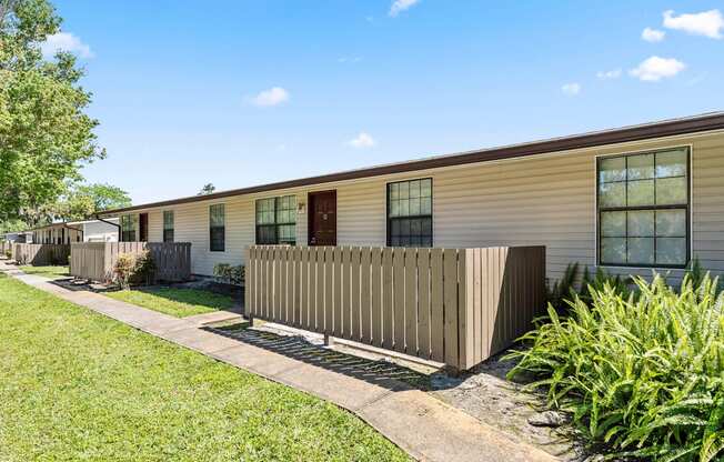 the exterior of a yellow house with a fence and grass