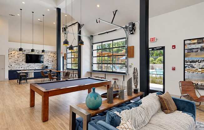 Resident lounge with a sofa, pool table and large windows at Icon Avondale Apartments in Decatur, GA.