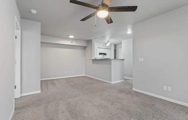 A room with a ceiling fan and carpeted floor.