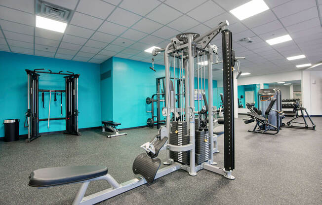 a gym with cardio equipment and weights in a room with blue walls at Presidio Palms Apartments, Tucson, Arizona