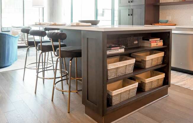 3-Bedroom model kitchen island with wicker baskets on the side and some stools at The Hamilton apartments in Dallas, TX