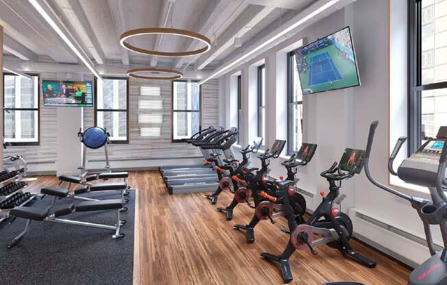 a gym with rows of exercise equipment and a tv